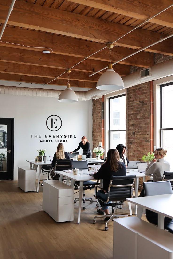 Bright loft office with white desks, brick walls and large windows
