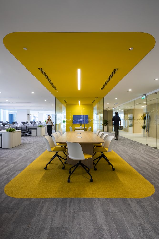 Meeting area in an open office defined by a yellow carpet and yellow ceiling panel